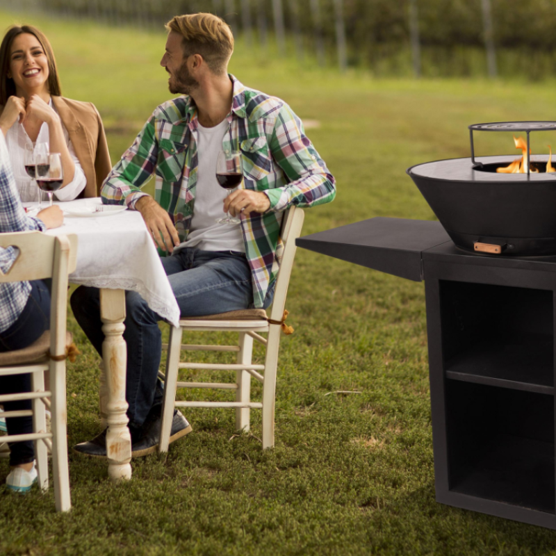 Barbacoa Purline modelo EFP 57 en funcionamiento al aire libre, con varias personas sentadas alrededor disfrutando del ambiente.